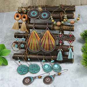 Detail of bohemian earrings set with turquoise beads and tassels on a wood stand