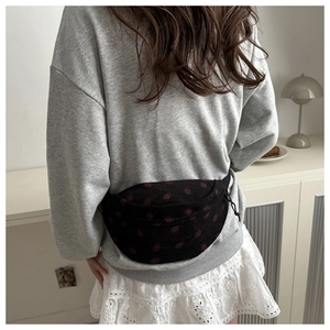 Detail of black waist bag with red strawberry print worn on back by model