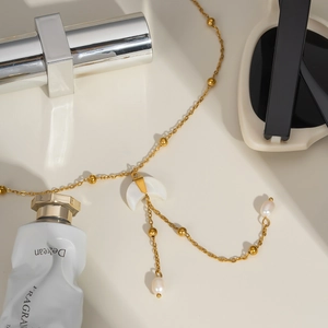 Macro detail of golden crescent moon pendant necklace with white stone and pearl tassels