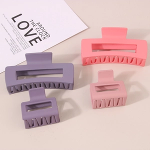 Set of four matte pink and purple hair claw clips in large and small sizes on beige background