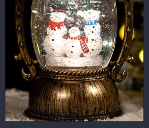 Macro view of vintage bronze Christmas lantern globe with three snowmen inside