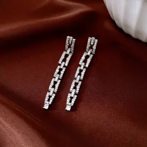 Orecchini a catena quadrata in argento con zirconi su sfondo di seta rosso scuro