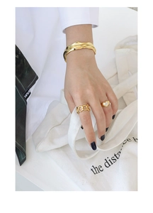 Golden irregular wave bangle and heart-shaped shell ring shown on a white background