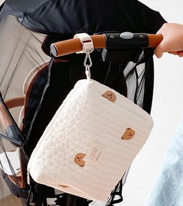 Detailed close-up of quilted baby stroller bag featuring brown bear embroidery and hooks
