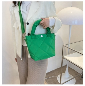 Detail of green quilted bucket bag with large diamond stitching and adjustable strap