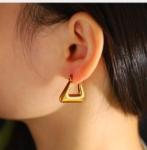 Close-up of a model wearing a geometric gold trapezoid earring made of stainless steel