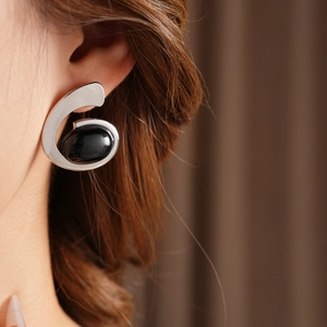 Close-up of geometric silver earring featuring a black oval gemstone on a model