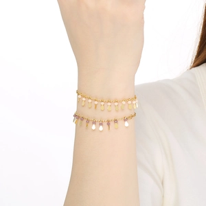 Chic multi-color beaded metal bracelets with teardrop charms on a model's wrist