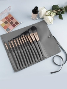 Detail of 12-piece professional makeup brush set with gray roll-up leather pouch