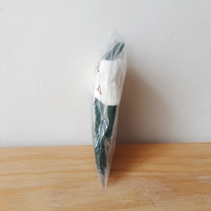 Detail of green knitted Christmas stocking with white cuff and red embroidery in clear pack