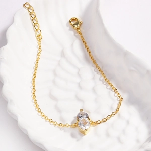 Close-up of golden double heart birthstone bracelet with marquise crystals on white shell tray