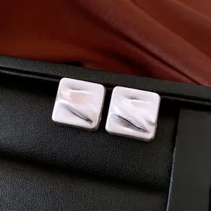 Boucles d'oreilles carrées minimalistes en argent avec texture brossée sur cuir foncé