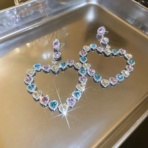 Vue détaillée de boucles d'oreilles cœur de luxe avec strass colorés sur un plateau