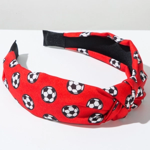 Detailansicht vom breiten geknoteten Stirnband mit Fußballmuster auf rotem Stoff