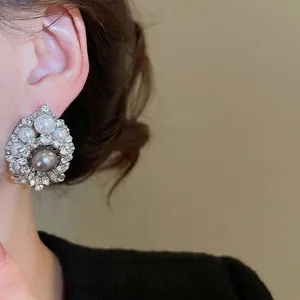 Elegant drop earrings featuring a large grey pearl surrounded by white pearls and crystals