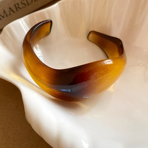Close-up of amber resin cuff bracelet with tortoiseshell texture on shell tray