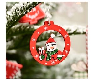 Detail of red wooden snowman ornament hanging on a snow-covered Christmas tree branch