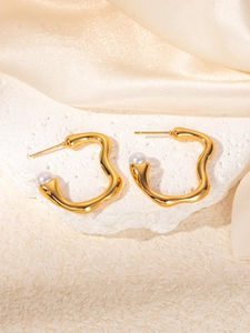 Detail of gold wavy stud earrings with round pearls on elegant champagne silk backdrop