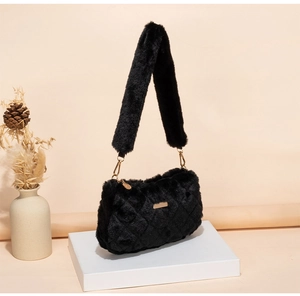 Detail of black plush shoulder bag with golden metal hardware and winter decor