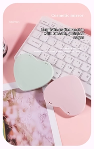 Detail of heart-shaped folding pocket mirrors in mint green and soft pink on a keyboard