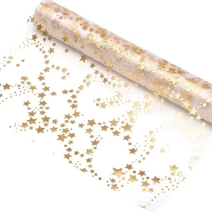 Detail of white semi-transparent mesh table runner with metallic gold star patterns