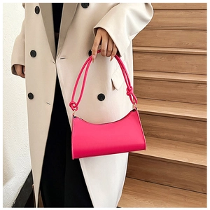 Detail of rose red baguette bag featuring knotted rope straps and glossy leather finish