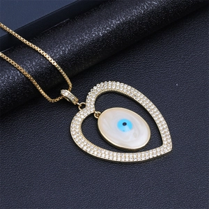 Close-up of golden heart pendant with pavé crystals and blue evil eye detail