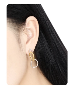 Detail of two-tone interlocking circular earrings featuring textured gold and silver finish