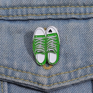 Creative green canvas sneaker enamel brooch pinned on a blue denim jacket pocket