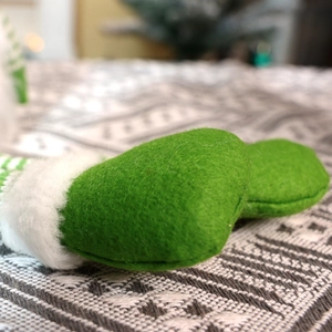 Macro detail of green felt Christmas gnome hat with white faux fur trim and knitted base