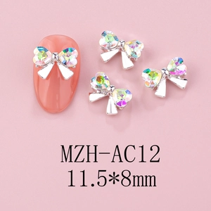 Detailed view of silver bow nail art charms with aurora rhinestones on pink nails