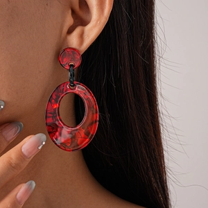 Close-up of model wearing vintage acrylic oval earrings with red tortoiseshell texture