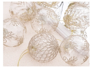 Close-up of 8cm clear PET Christmas balls with gold glitter snowflakes and swirls
