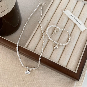 Vintage heart jewelry set with pearls and silver beads for women on a display stand
