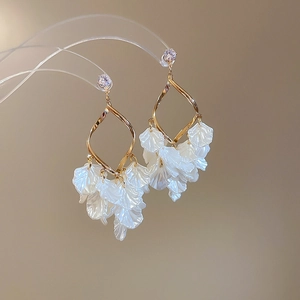 Detail view of gold tassel earrings with zircon, twisted diamond frame and white petals