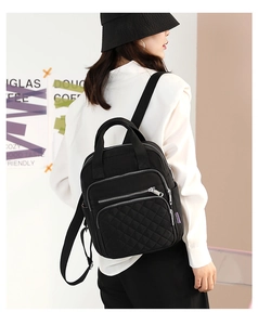 Detailed back view of a black quilted nylon backpack featuring multi-layer zippers