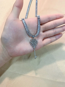Macro shot of silver key pendant with rectangular cut zircon stones on tennis chain