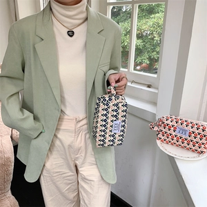 Détail de la trousse de maquillage en velours côtelé avec motif floral et poignée latérale