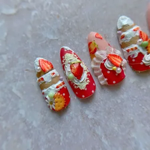 Detailed macro view of 3D strawberry dessert themed press-on nails with cream and pearls