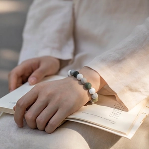 Bracelet en marbre naturel gris et pierres vertes posé sur un livre ouvert élégant