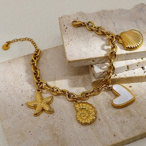 Macro detail of 18K gold-plated nautical chain bracelet with starfish and shell charms