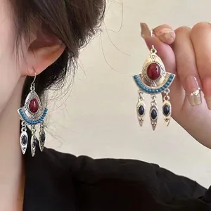 Detailed view of bohemian fan-shaped earrings with red agate and blue turquoise stones