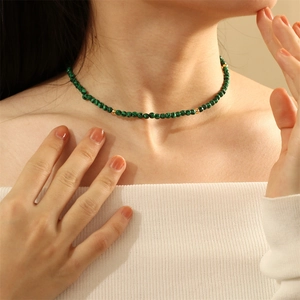 Close-up of green malachite stone beaded necklace with gold metal accents on neck