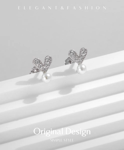 Close-up of s925 silver heart stud earrings with sparkling crystals and white pearls