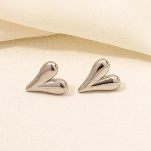 Macro detail of polished silver heart earrings showing smooth texture and mirror finish