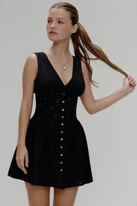 Détail de la robe courte noire à col en V avec broderie ajourée et boutons décoratifs