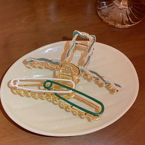 Elegant safety pin and pearl hair claw clips on a tray, stylish metal hair accessories
