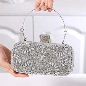 Detail of silver evening clutch bag featuring intricate floral rhinestone patterns and handle