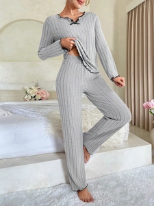 Detail view of light gray ribbed loungewear set with black ruffled edges and a small bow