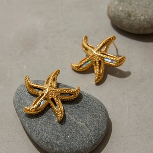 Detailed view of 18K gold plated starfish earrings with abalone shell inlay on stones
